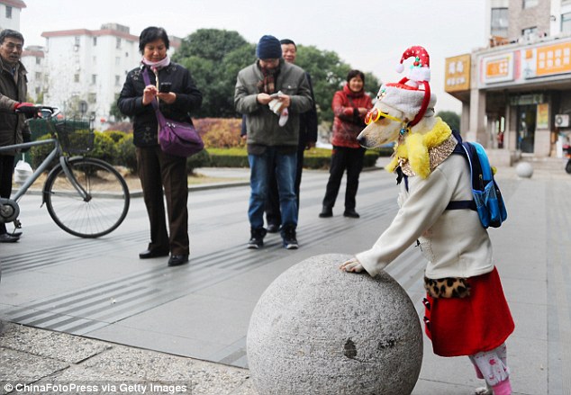 Xiaoniu, wearing a Santa hat and rucksack, leans on a sculpture at Pudong Zhengdajiayuan housing estate
